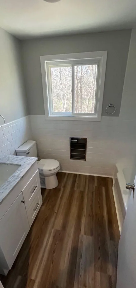Bathroom remodel with subway tile, marble-top vanity and plank flooring by Tauro Builders