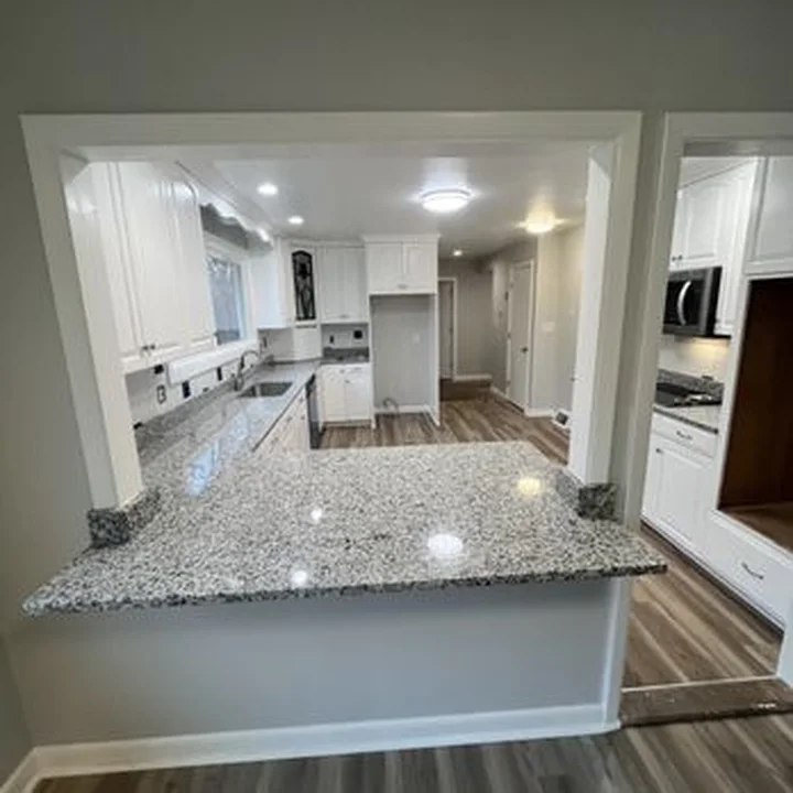 White kitchen with granite peninsula by Tauro Builders
