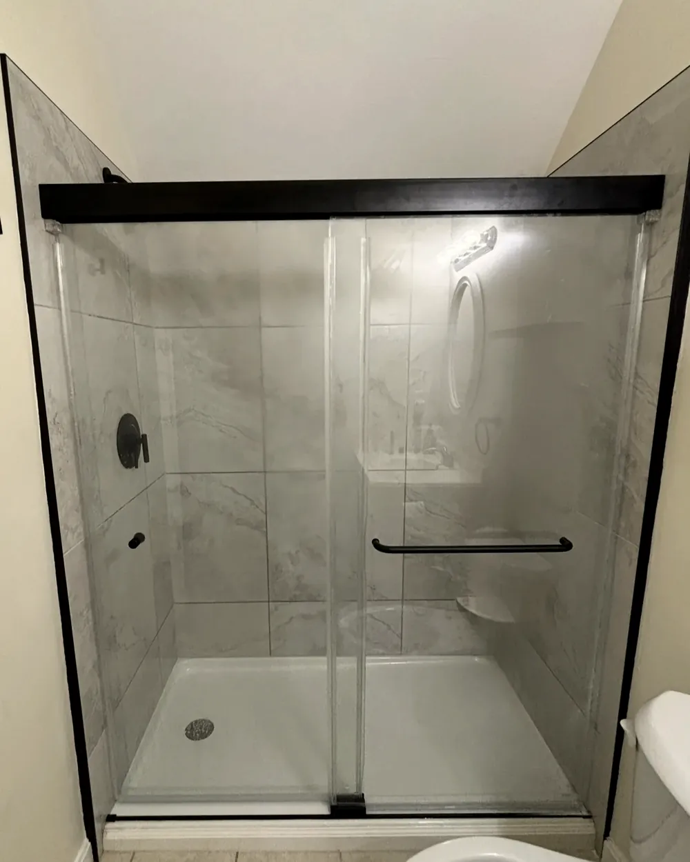 Tiled shower with glass enclosure by Tauro Builders